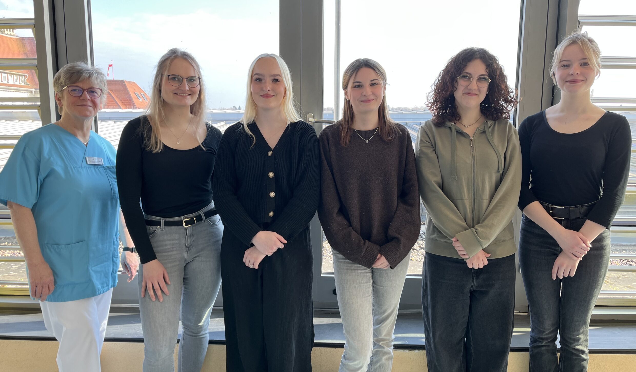Fünf Schülerinnen der PFK-Winterklasse stehen zusammen mit Praxisanleiterin Ulrike vor einem großen Fenster