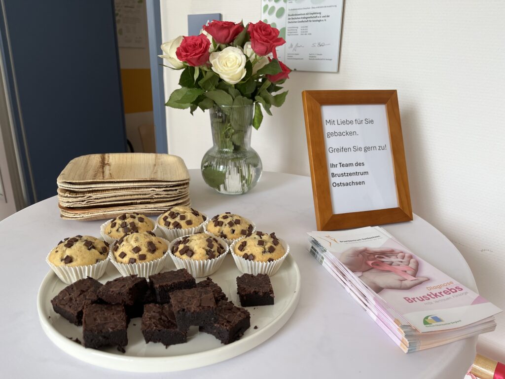 Ein Begrüßungstisch des BrustZentrum OstSachsen mit Muffins und Blumen