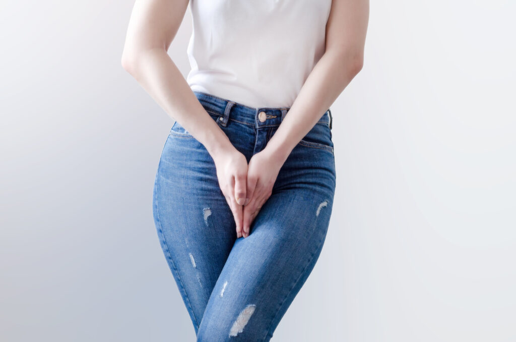 Young woman in jeans standing with hands between legs