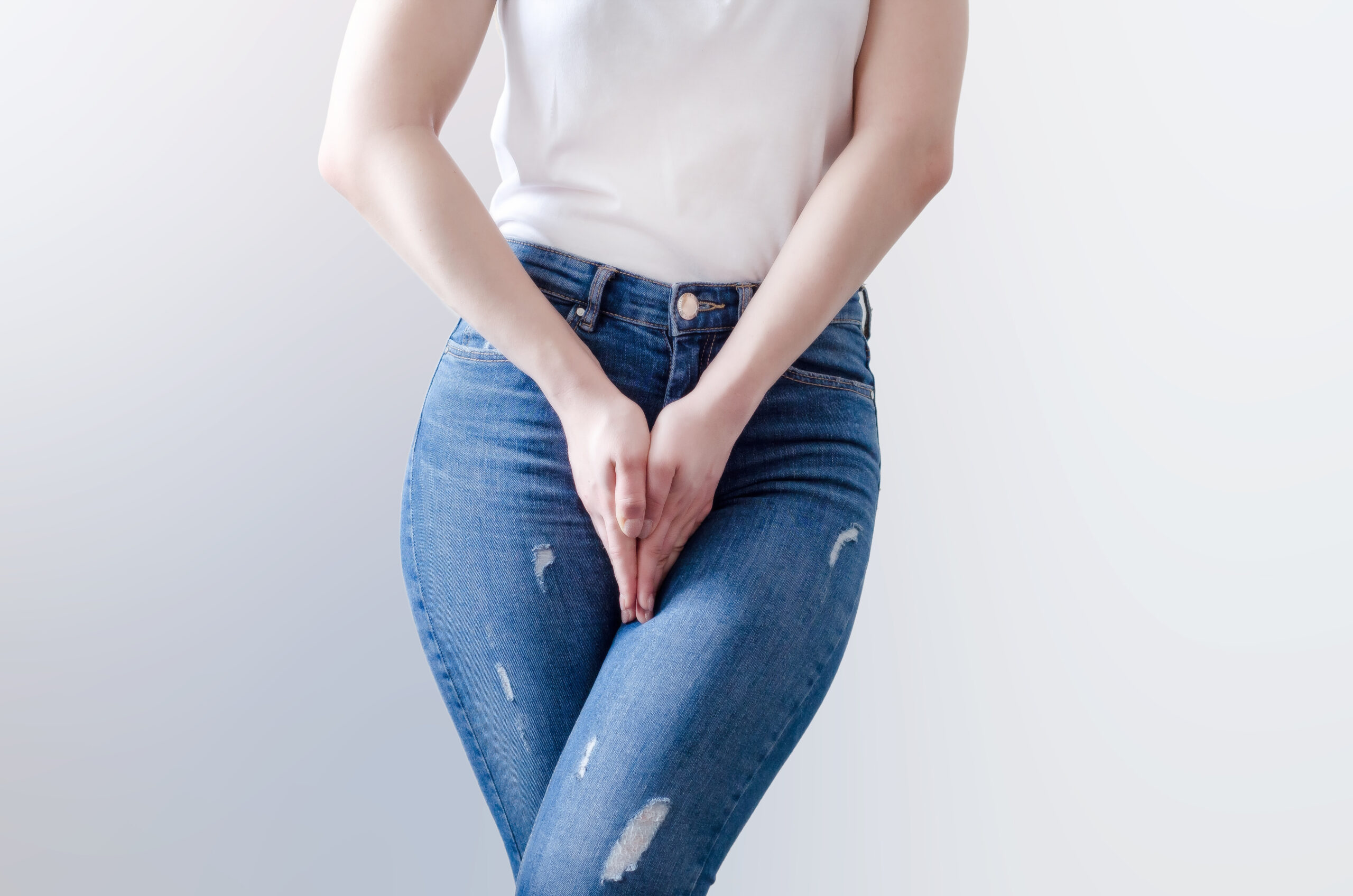 Young woman in jeans standing with hands between legs