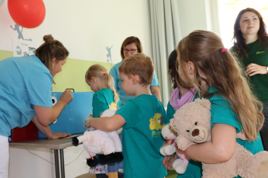 Kinder warten beim Teddyklinik-Röntgen und schauen gespannt, was passiert